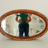 Antique oval mirror with beveled glass in wood and stucco, 19th century