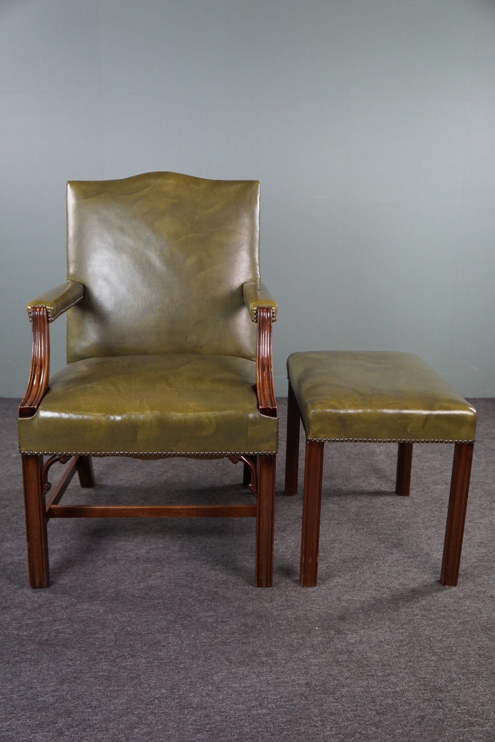 Elegant armchair and footrest in English green leather