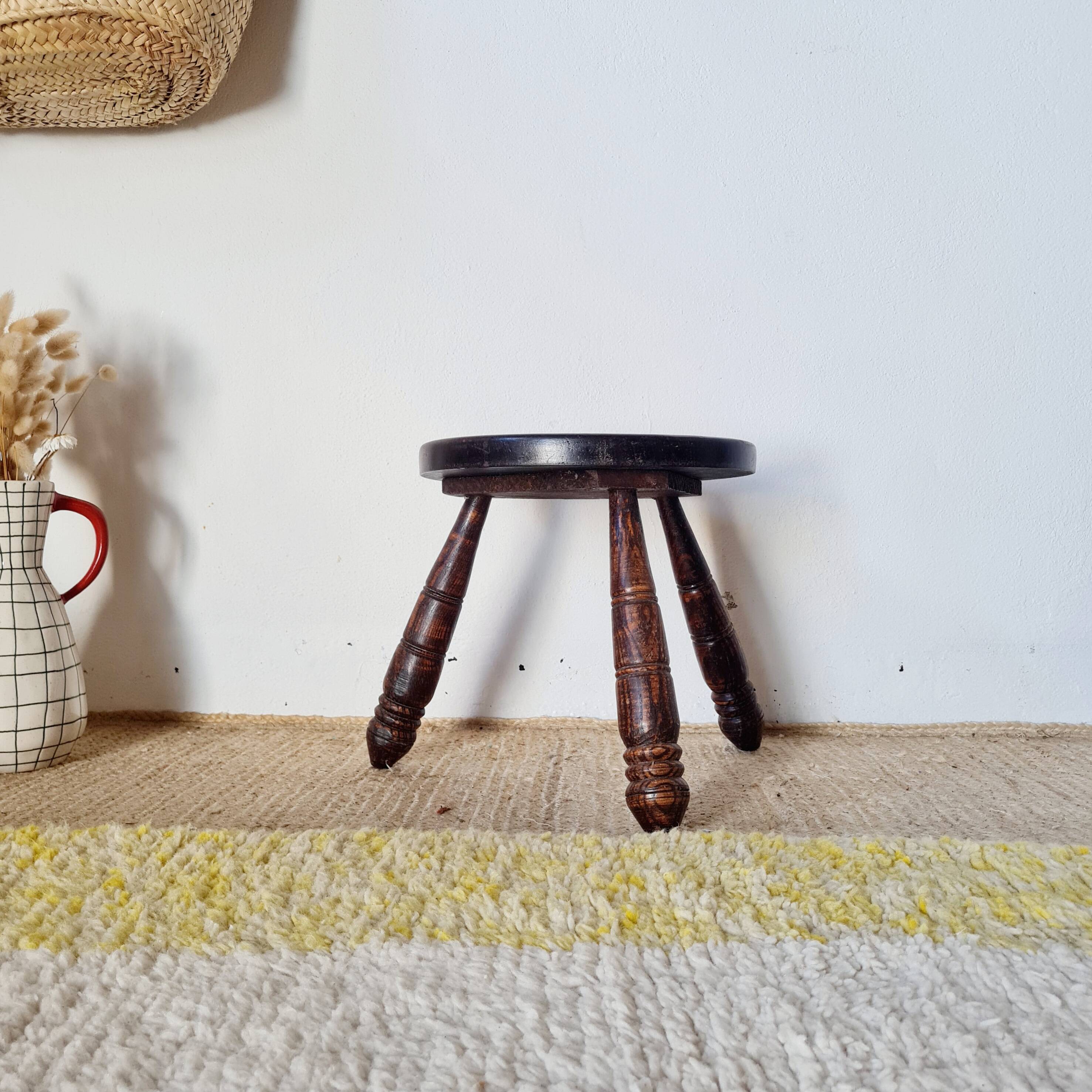 Small brutalist tripod stool made of turned wood.