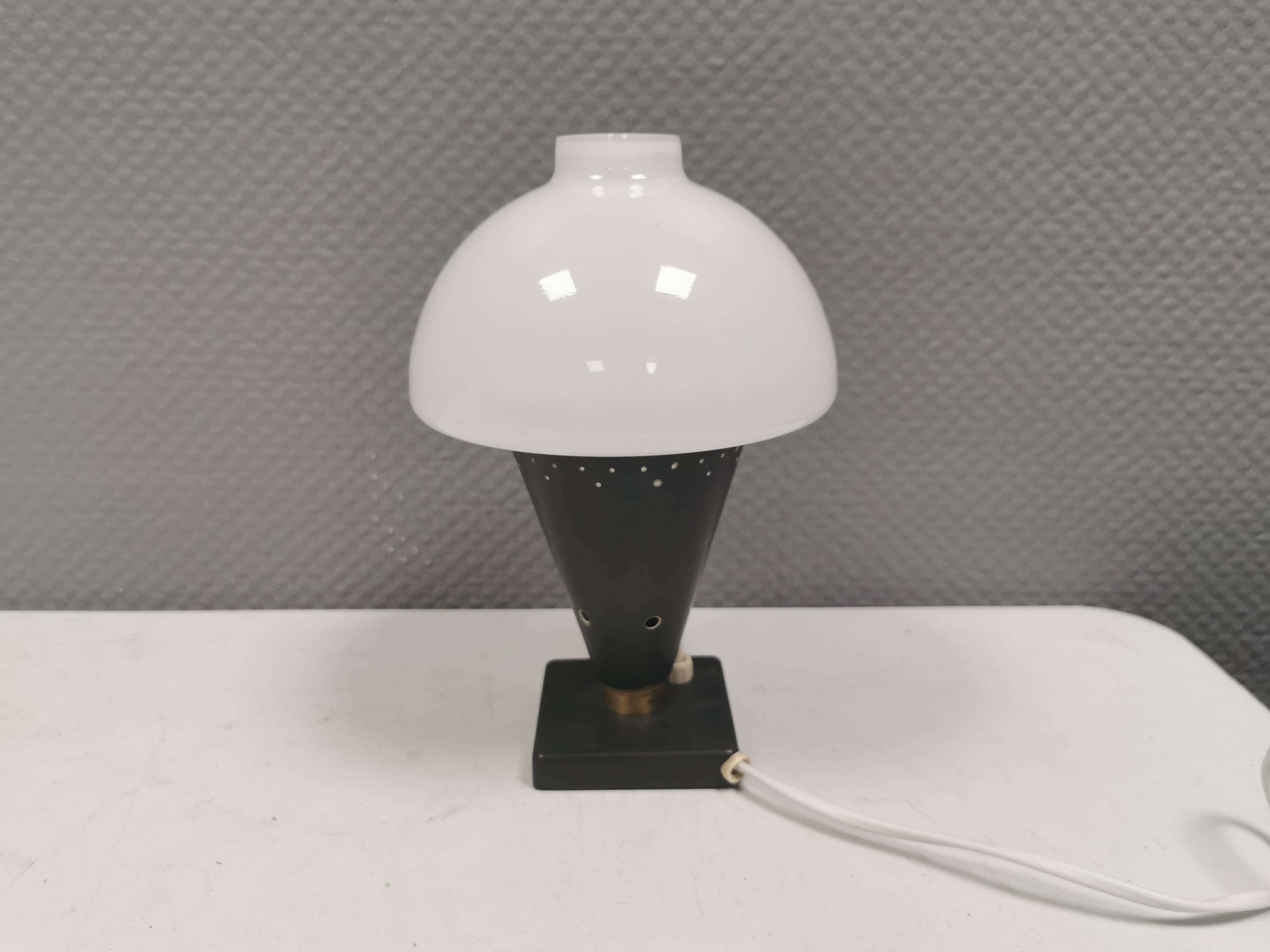 Small stylish table lamp with perforations and milky white opal glass shade