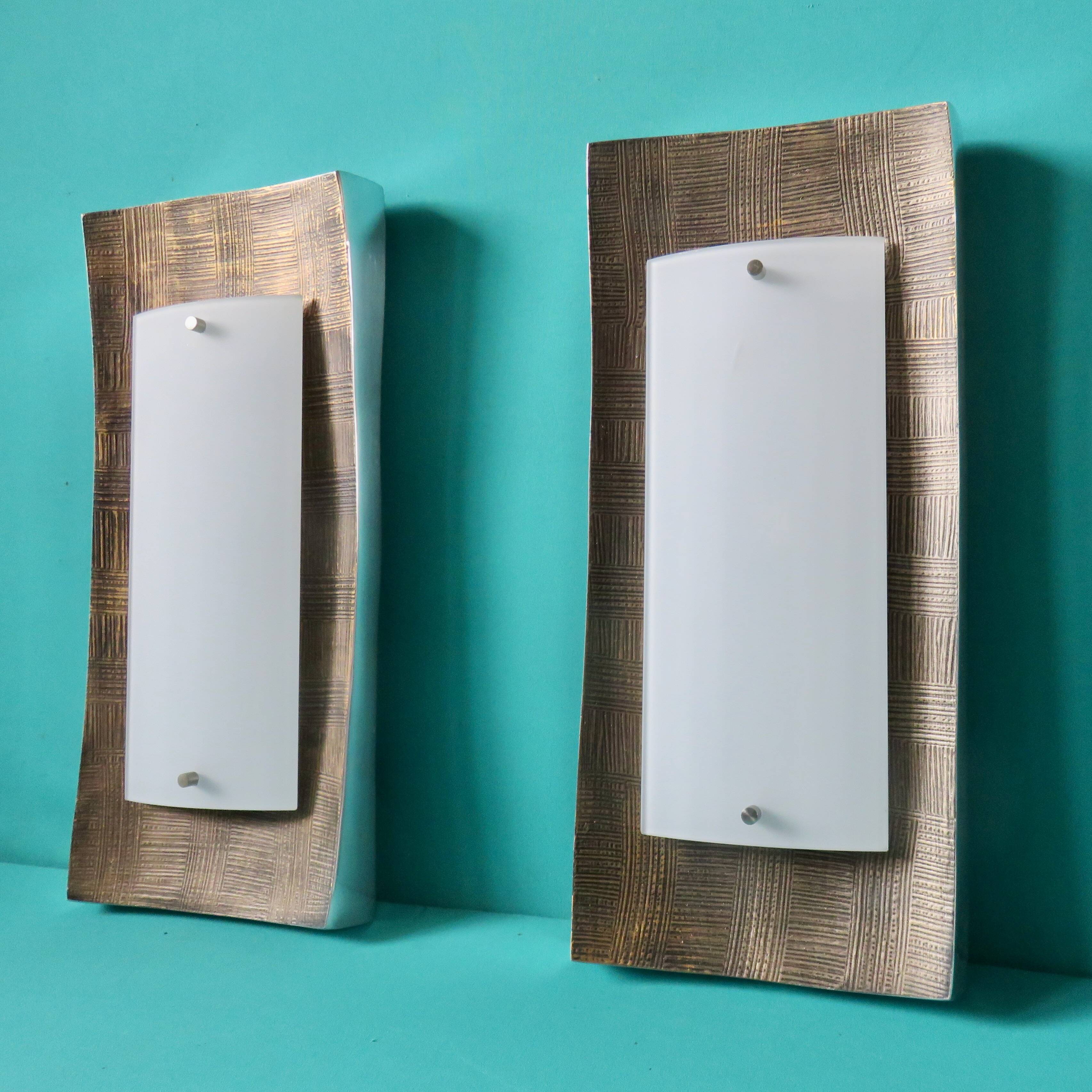 Pair of wall sconces in gold-plated alloy with bas-relief and opaline glass. Germany, 1980