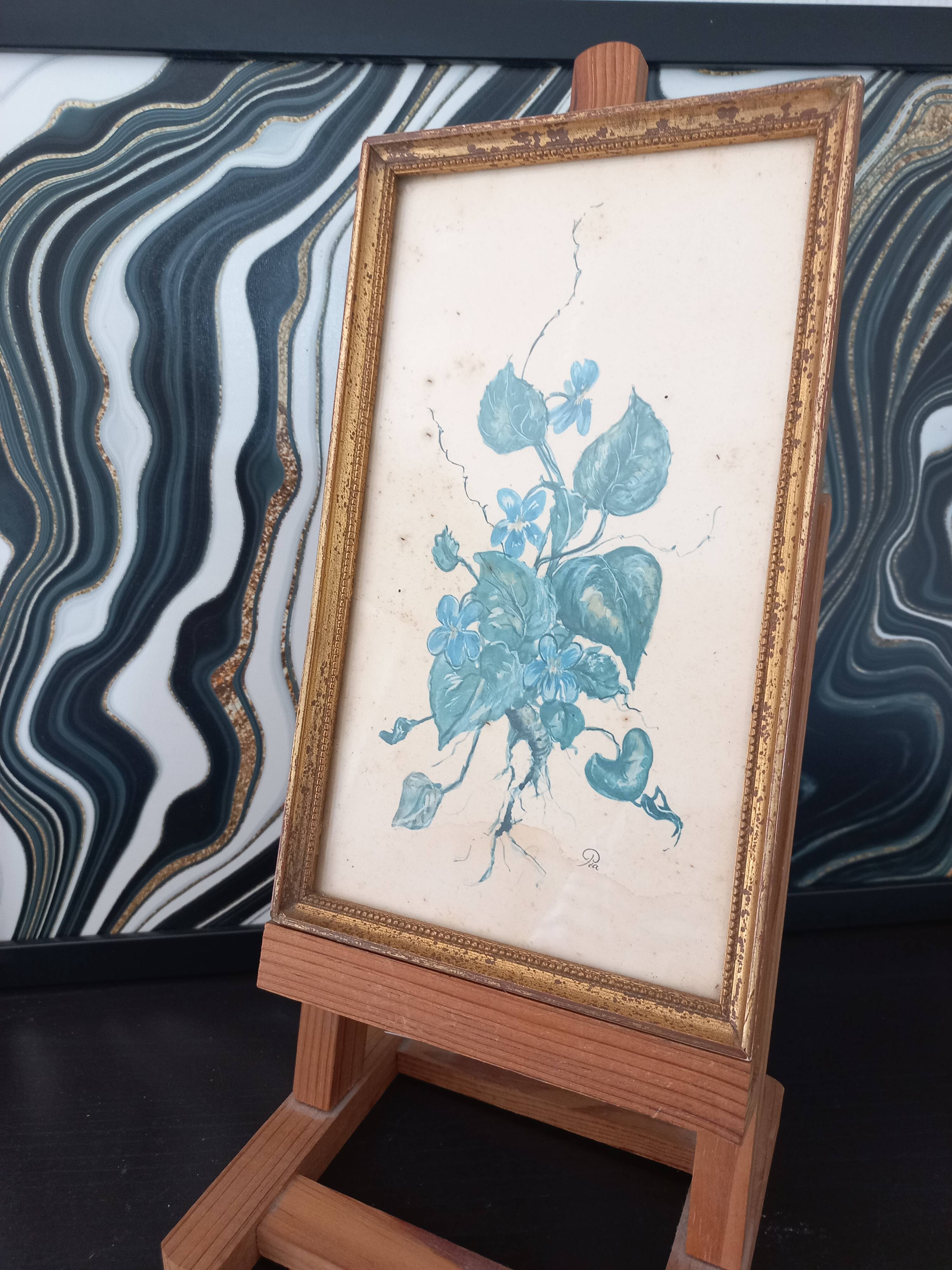 Decorative table with vintage blue flowers in a golden frame.