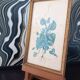 Decorative table with vintage blue flowers in a golden frame.