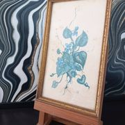 Decorative table with vintage blue flowers in a golden frame.