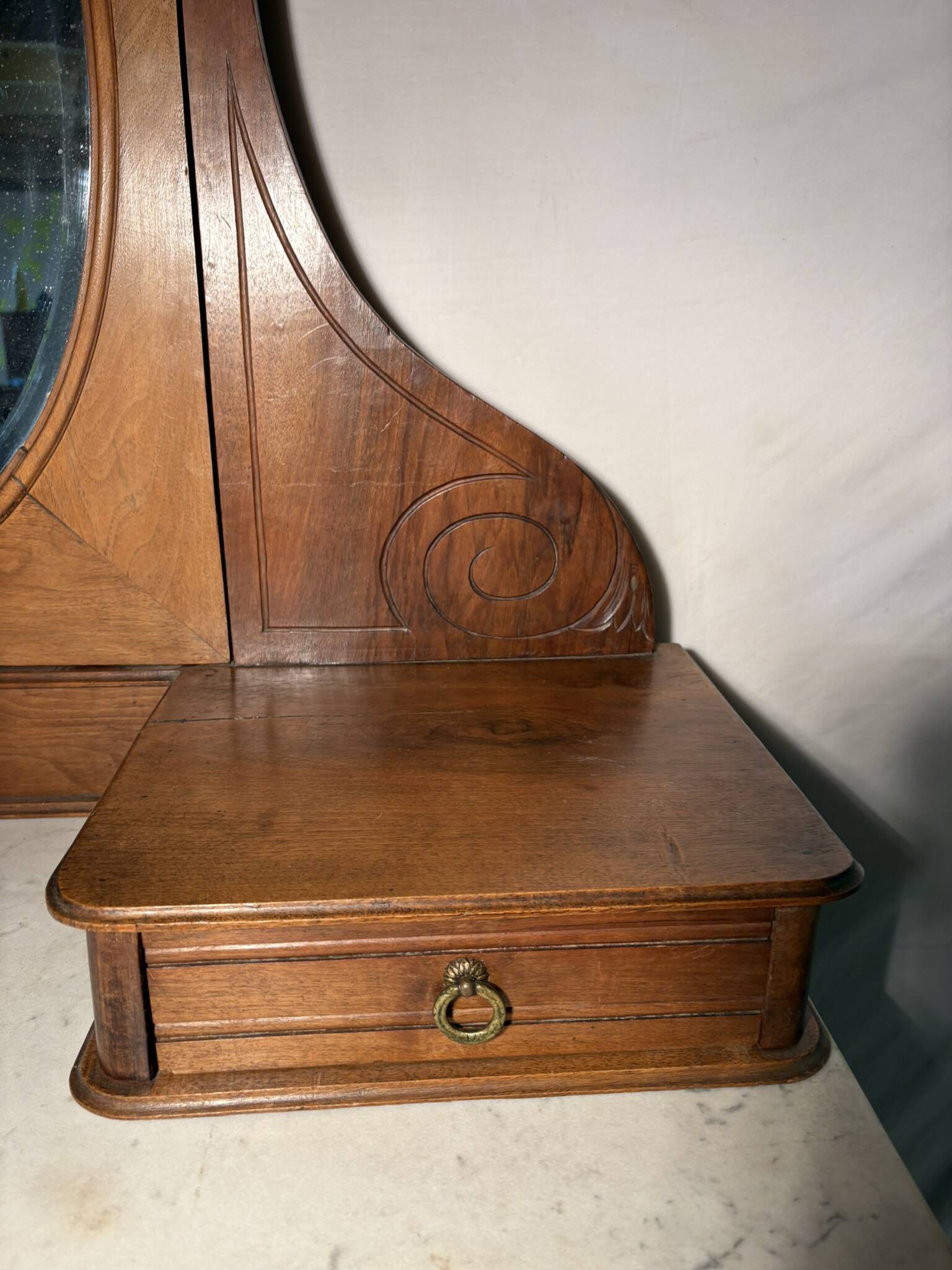 Antique carved wooden dressing table with marble and tilting oval mirror.