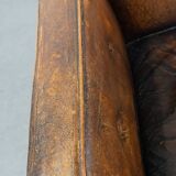 Fauteuil ancien en cuir de mouton sur roulettes et patiné