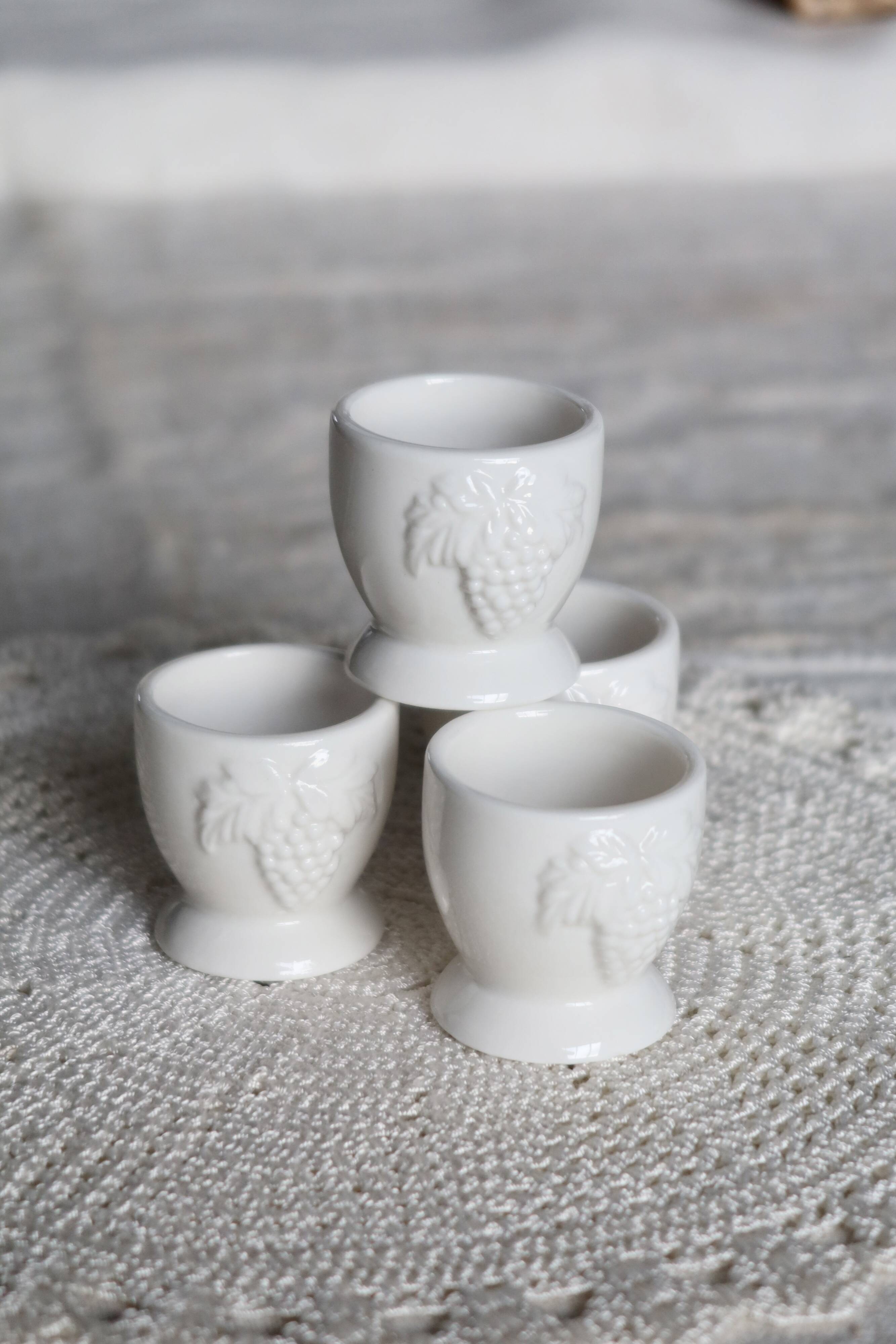 Vintage white porcelain egg cups with fruit motif.