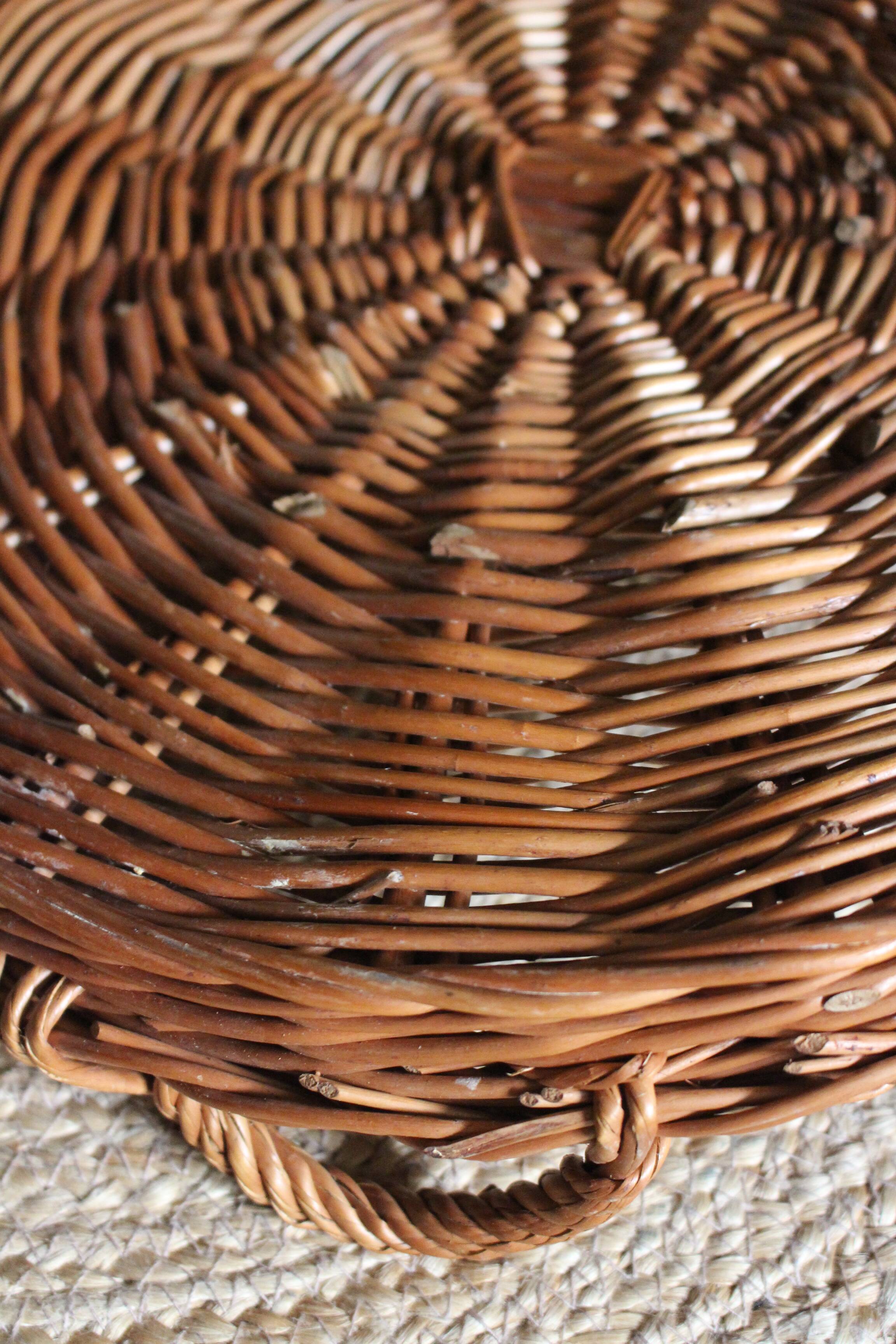 Large round dark wicker tray with two handles.