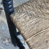 Antique black turned wood corner chair with a straw seat.