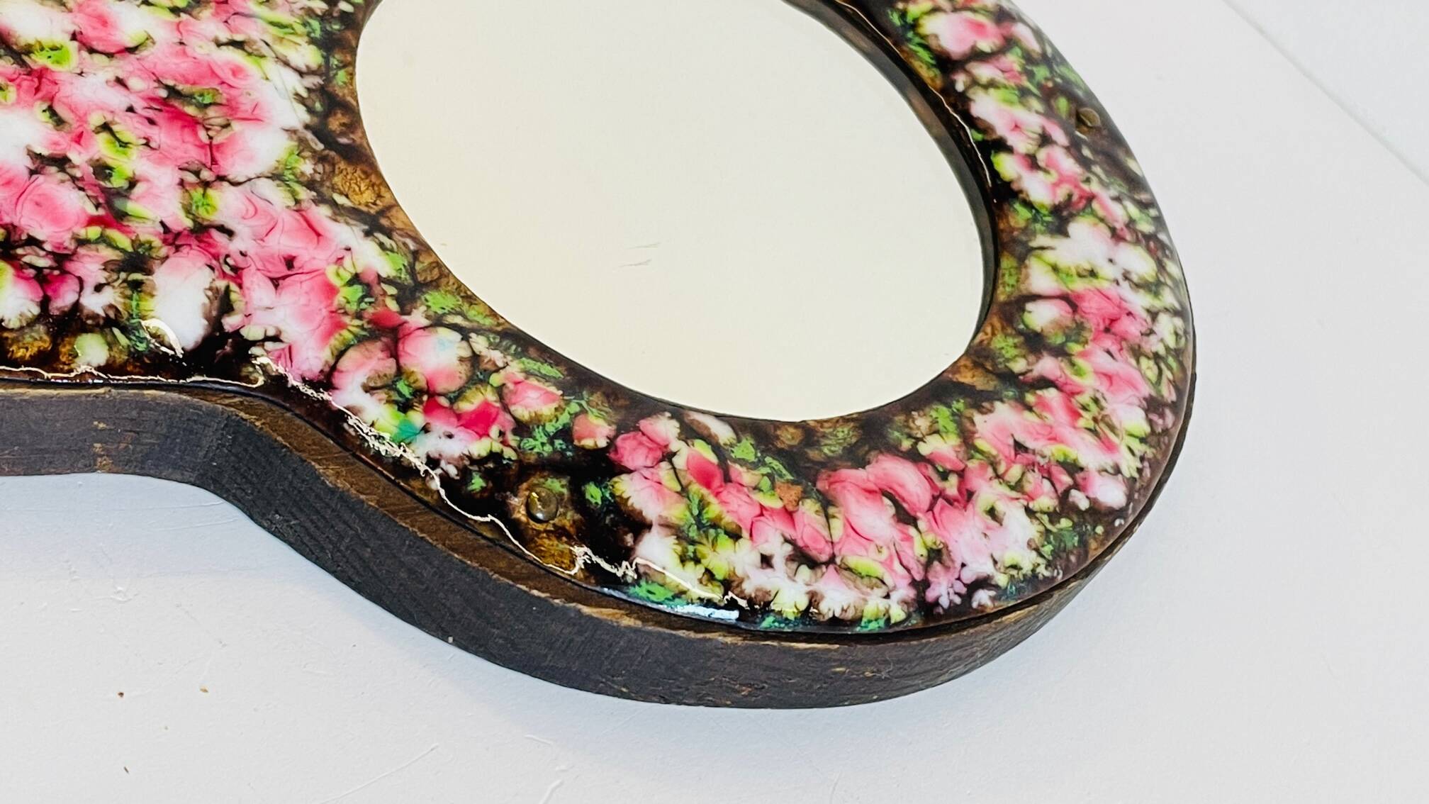 Vintage enameled metal hand mirror on wood