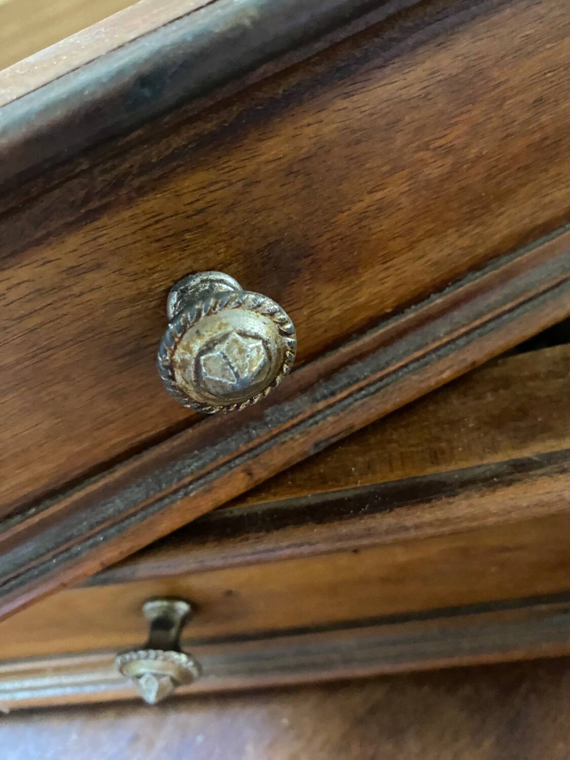 2 tiroirs en bois au bouton en laiton ciselé .