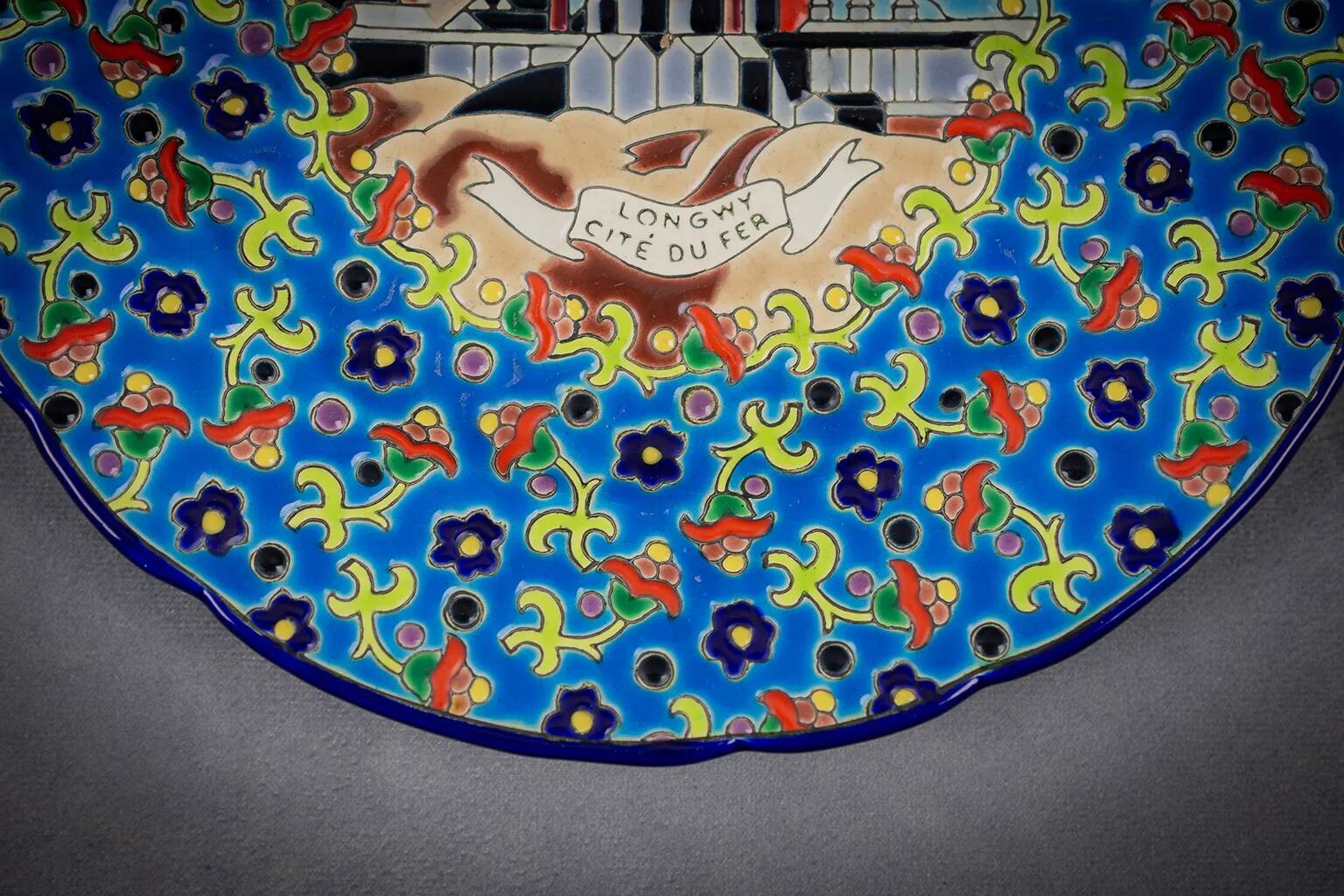 Longwy plate with polychrome enamels, decorated with the "City of Iron" motif.