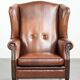 Sheepskin wingback armchair in a warm cognac colour with refined nailhead trim