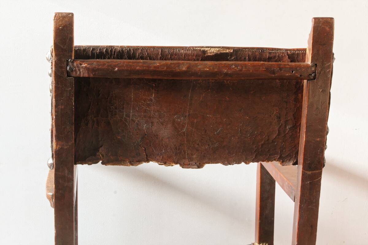 Antique armchair in walnut and studded leather, 17th century