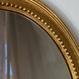 Oval-shaped wooden mirror in gold color