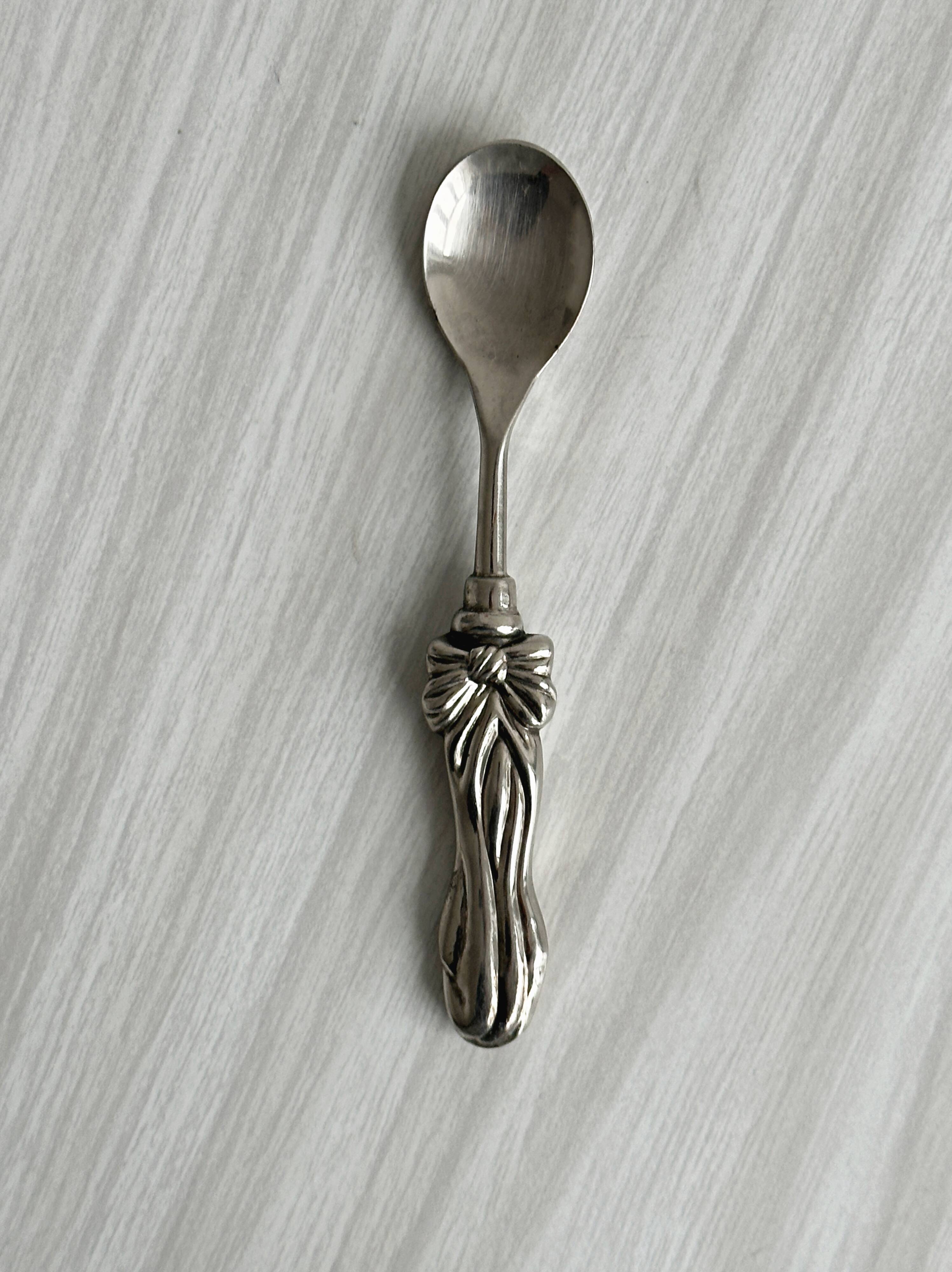 Antique small spoons with a metal bow design
