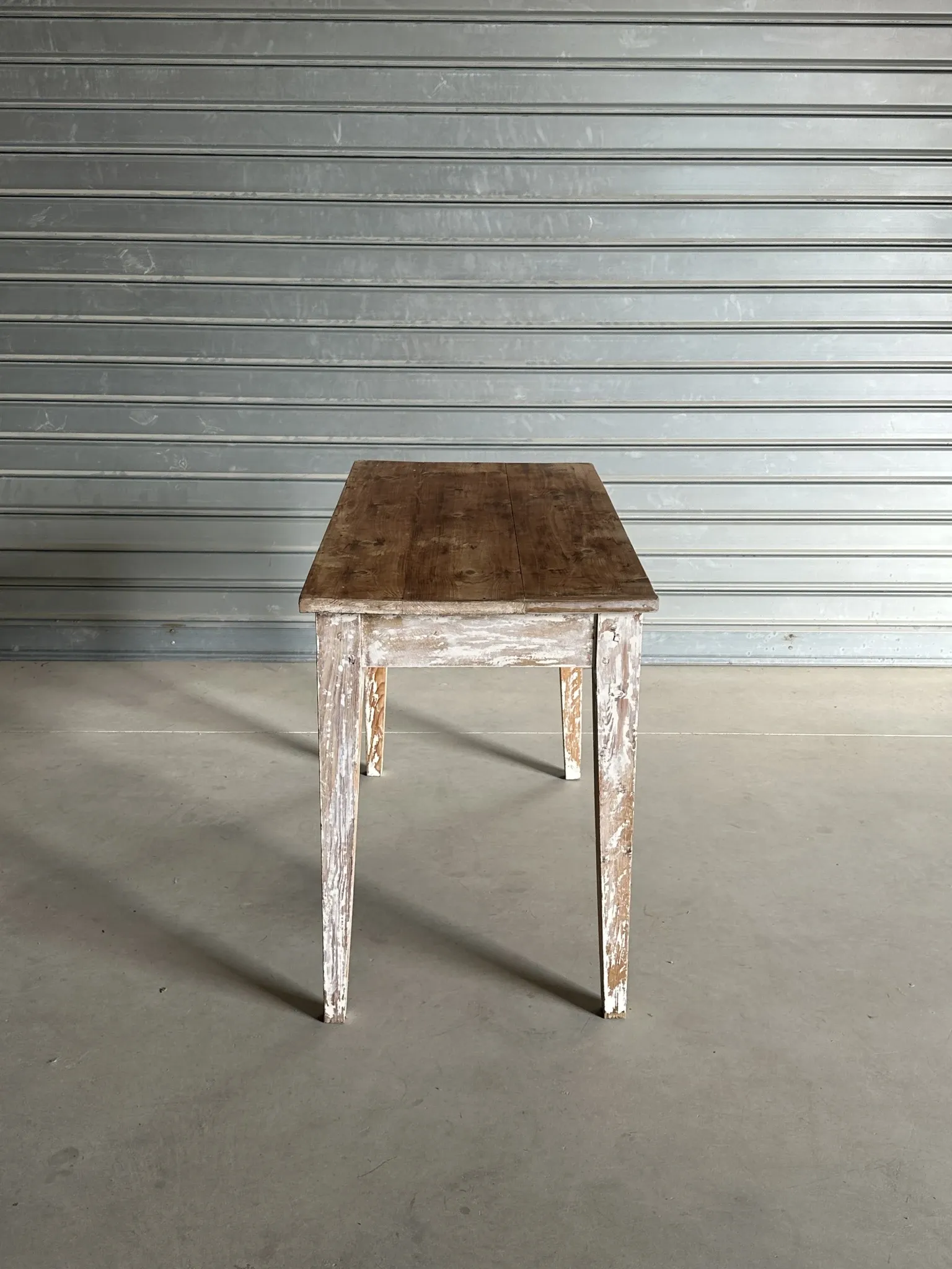 Vintage table made of raw wood with a distressed white base.