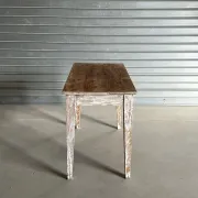 Vintage table made of raw wood with a distressed white base.