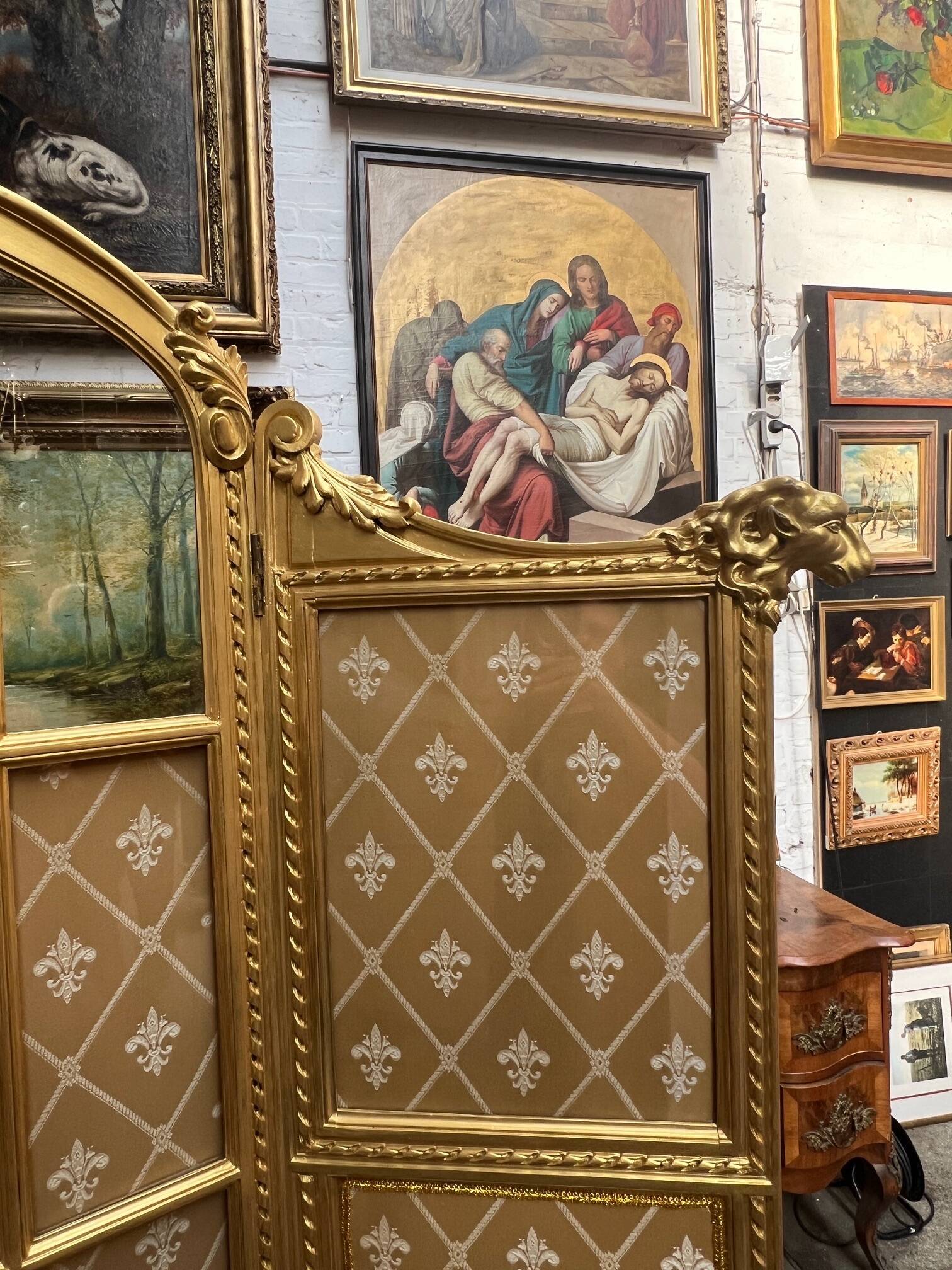 Paravent en bois doré décoré dans le style Louis XVI, orné de têtes de bélier.