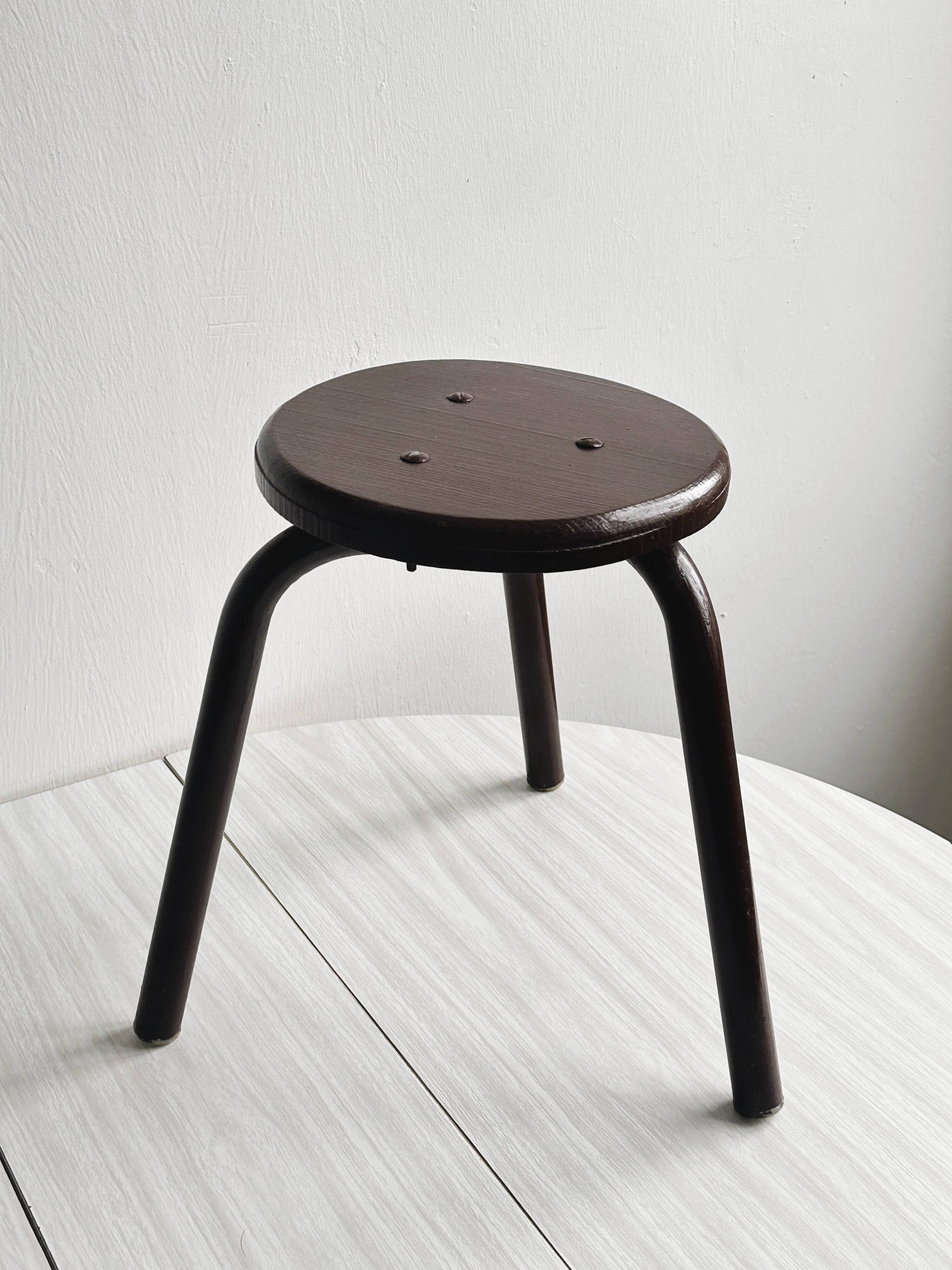 Dark brown metal stool, minimalist three-legged design