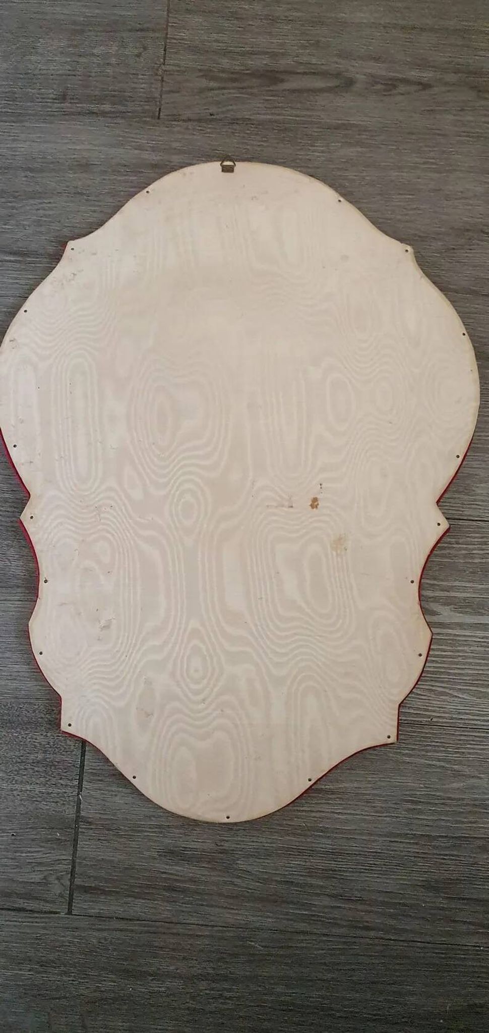 Vintage mirror with a scalloped shape in burgundy velvet and a golden trim.