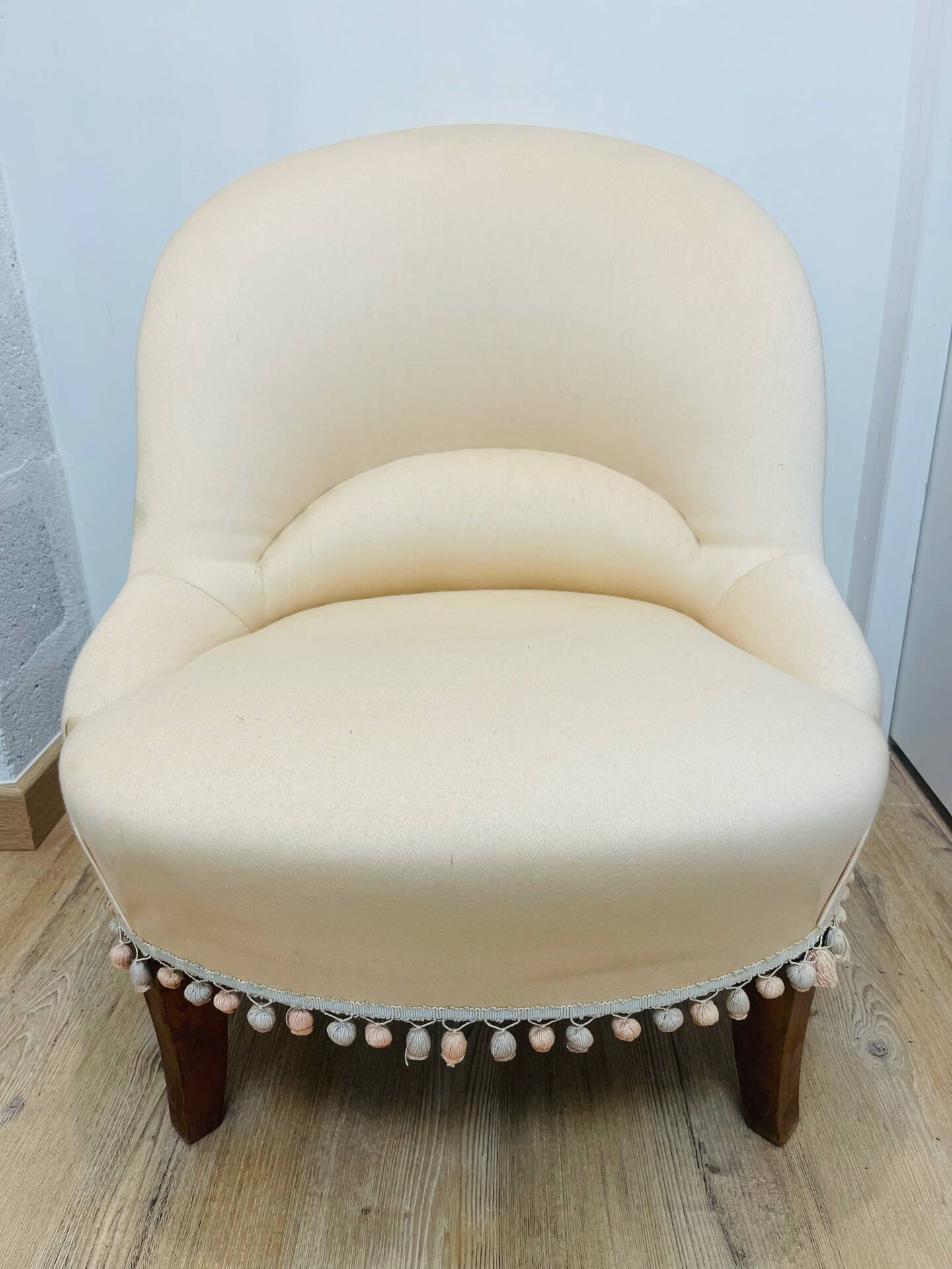 Pale pink upholstered armchair with wooden legs.
