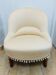 Pale pink upholstered armchair with wooden legs.