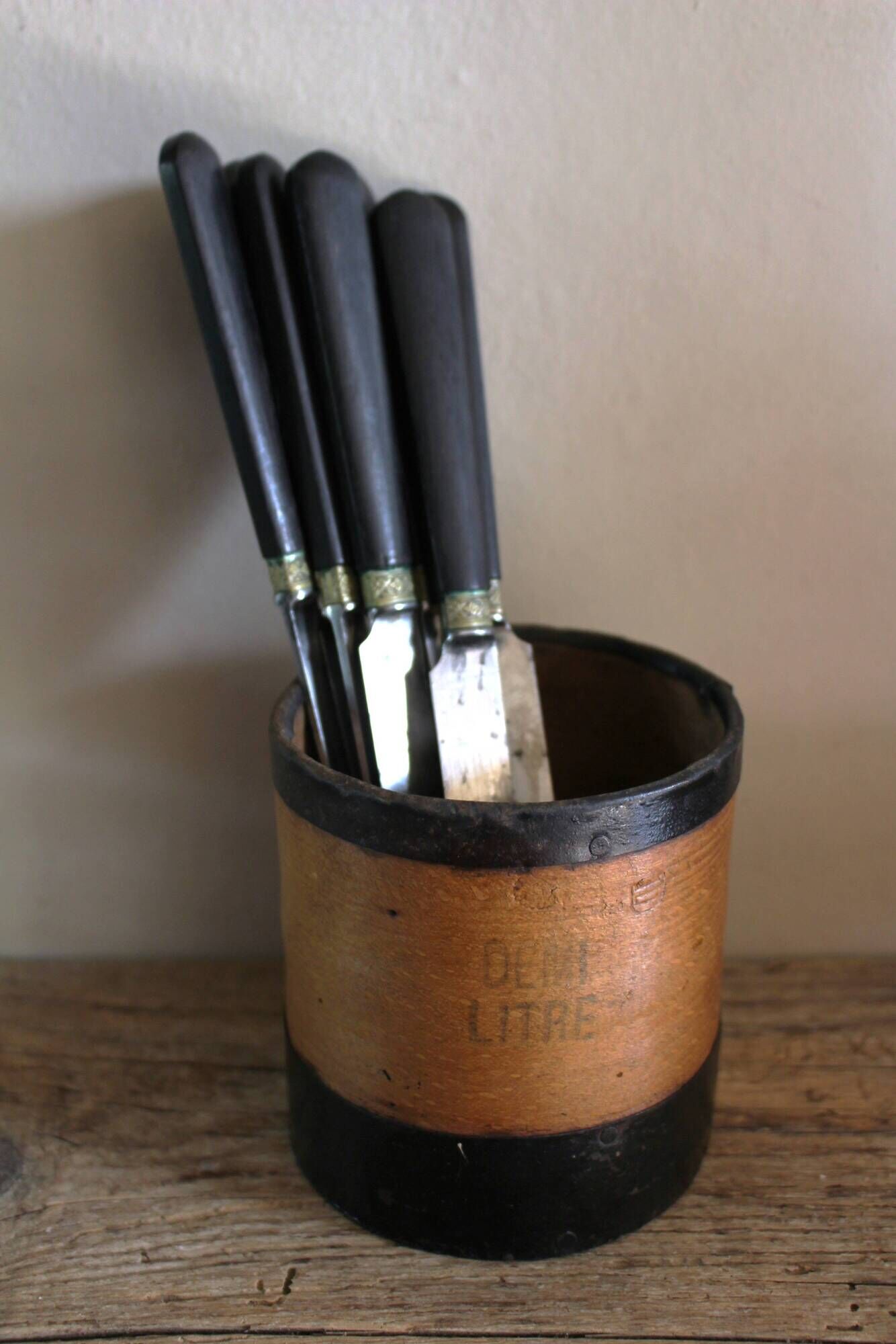 A set of 8 knives with black wooden handles and bolsters.