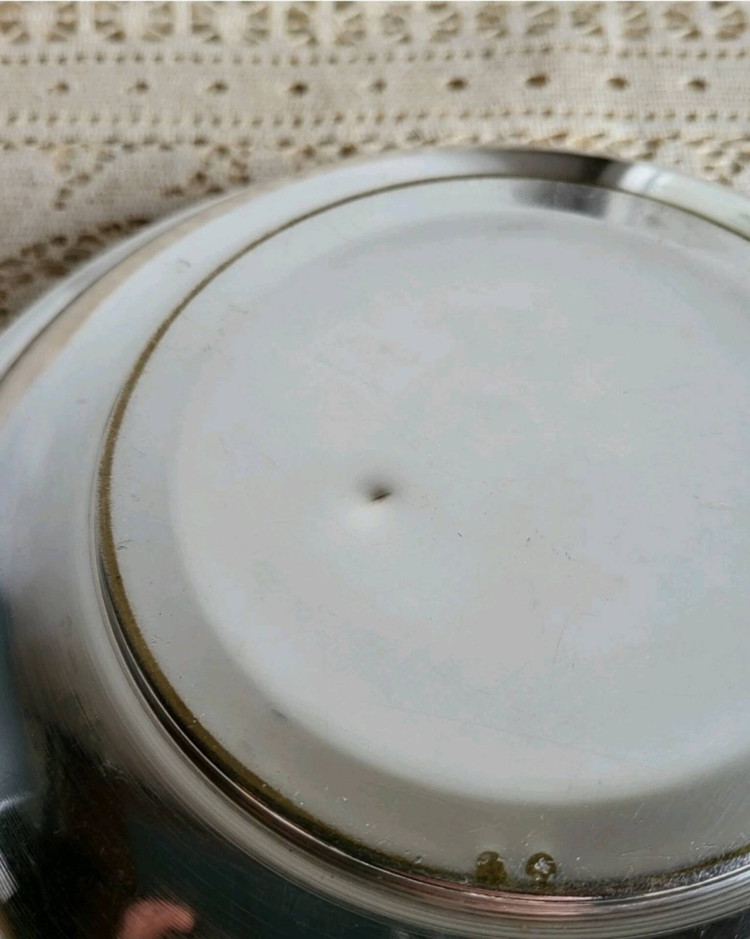 Shallow round metal plate with pearl row decoration.