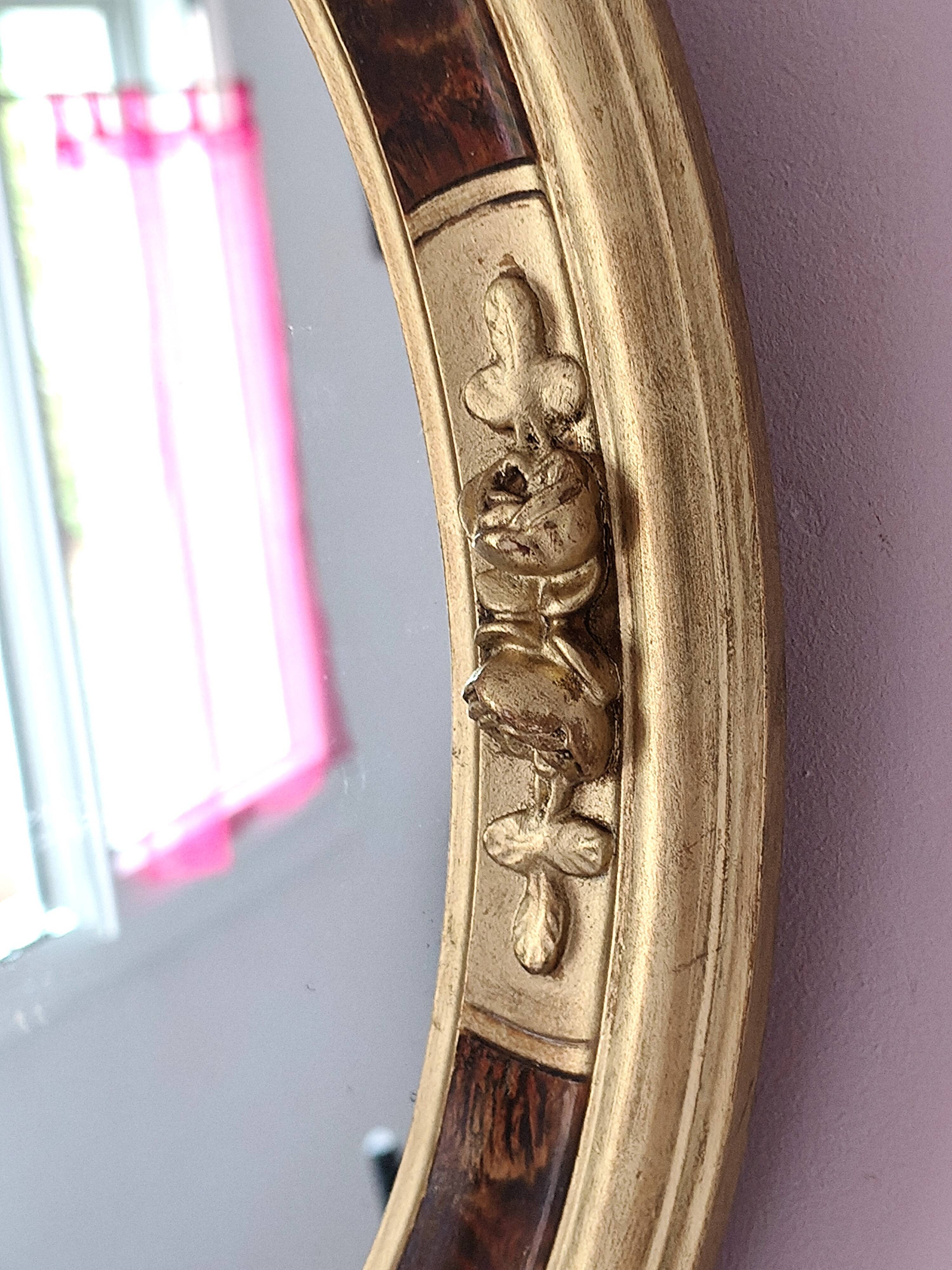 Antique medallion mirror with a gilded and relief-carved frame.