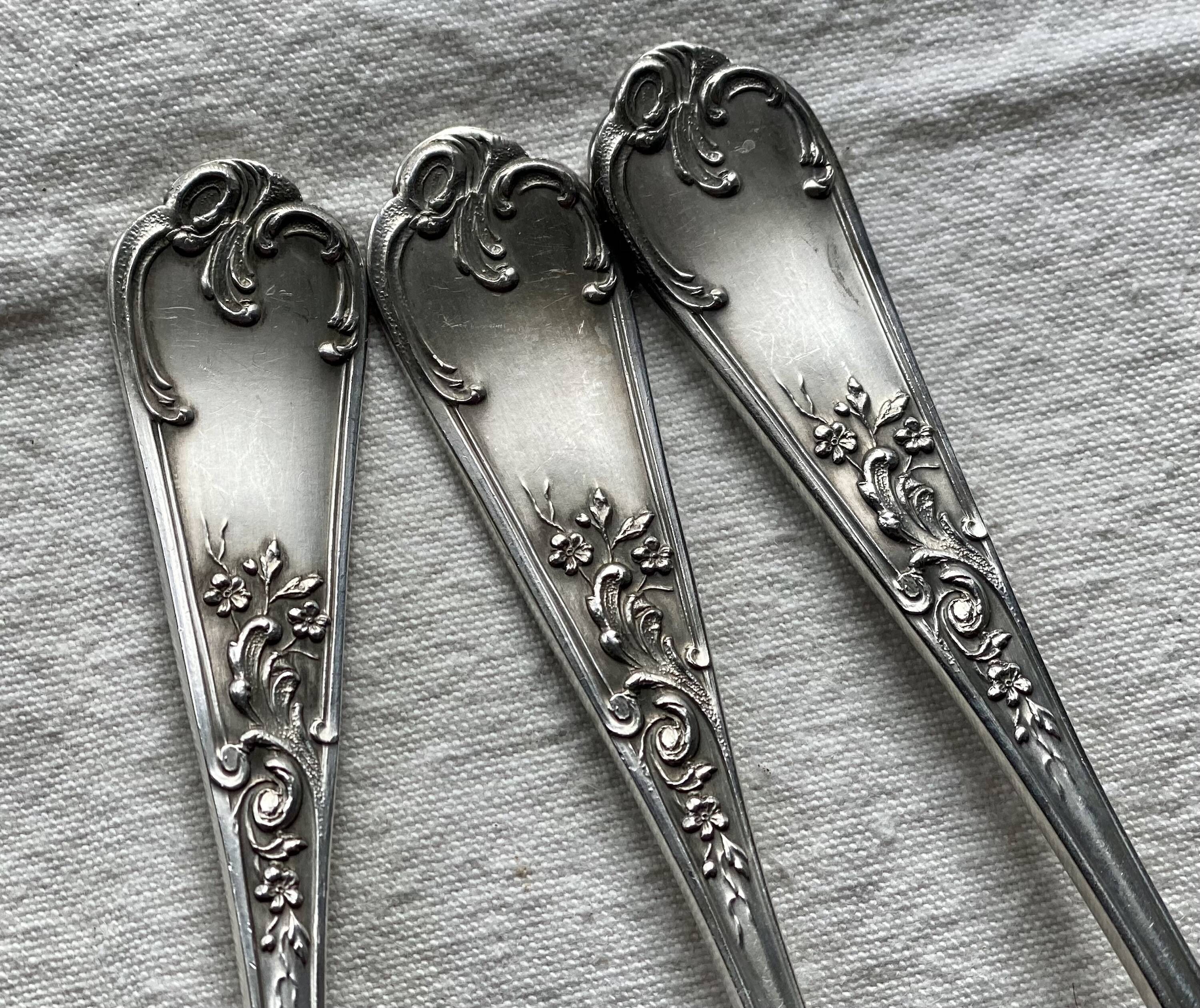 Set of 12 small silver-plated metal spoons in Art Nouveau style.