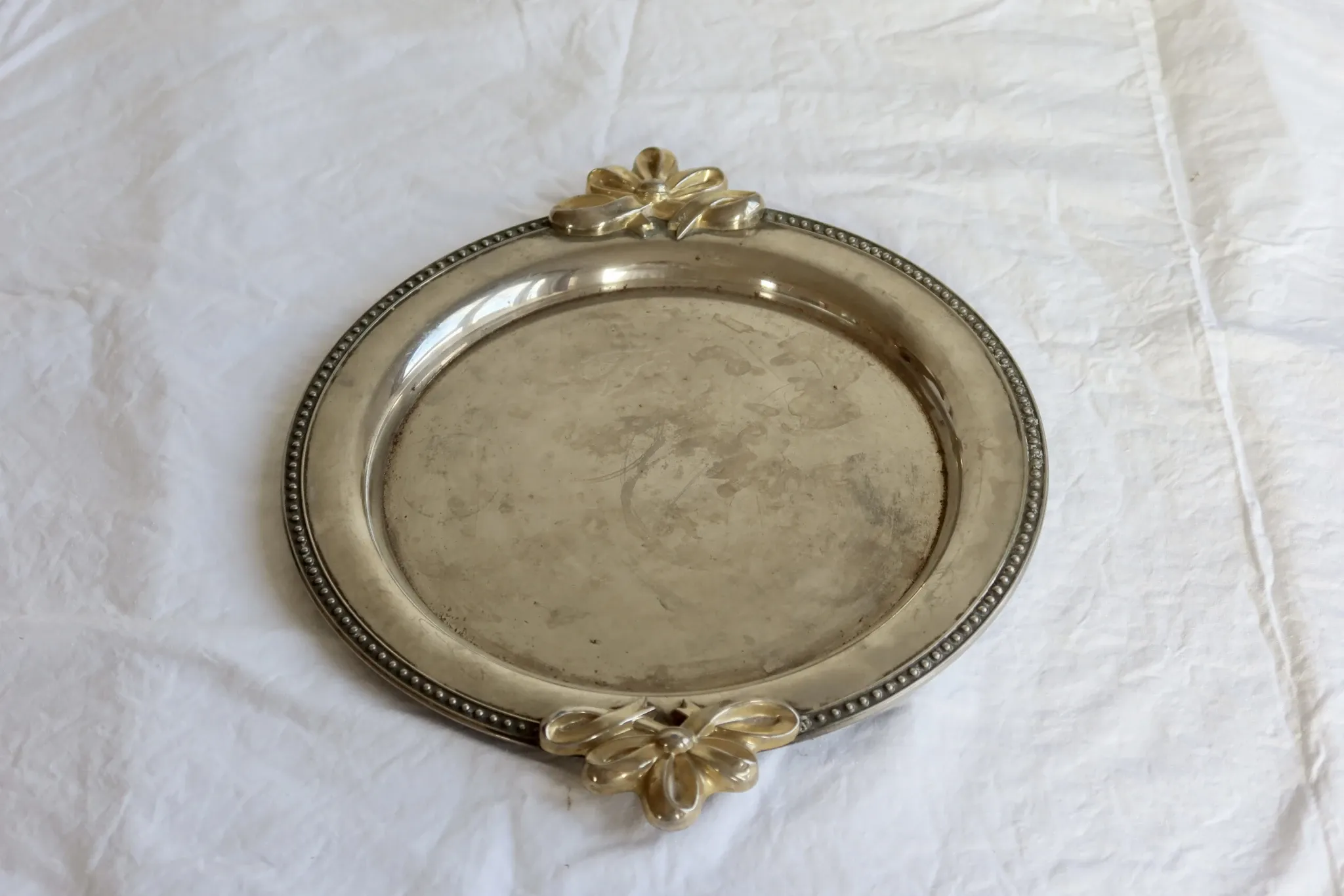 Vintage silver-plated serving tray with bow handles.