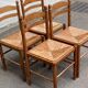 4 solid wood kitchen chairs with straw seats in a country farmhouse style.