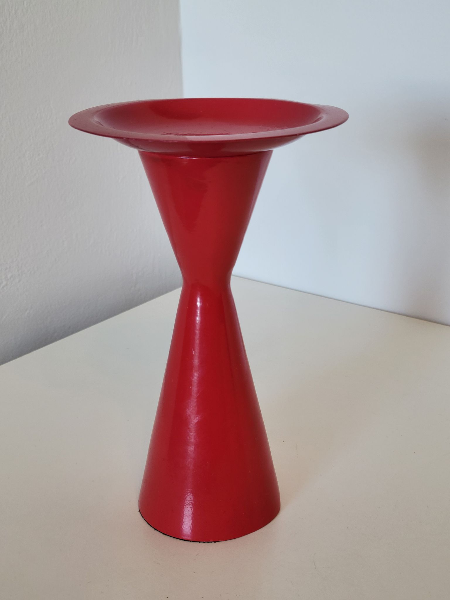 Vintage design candlestick in red metal in the shape of an hourglass
