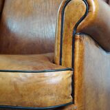 Subtle sheepskin wing chair in good condition on brass front wheels