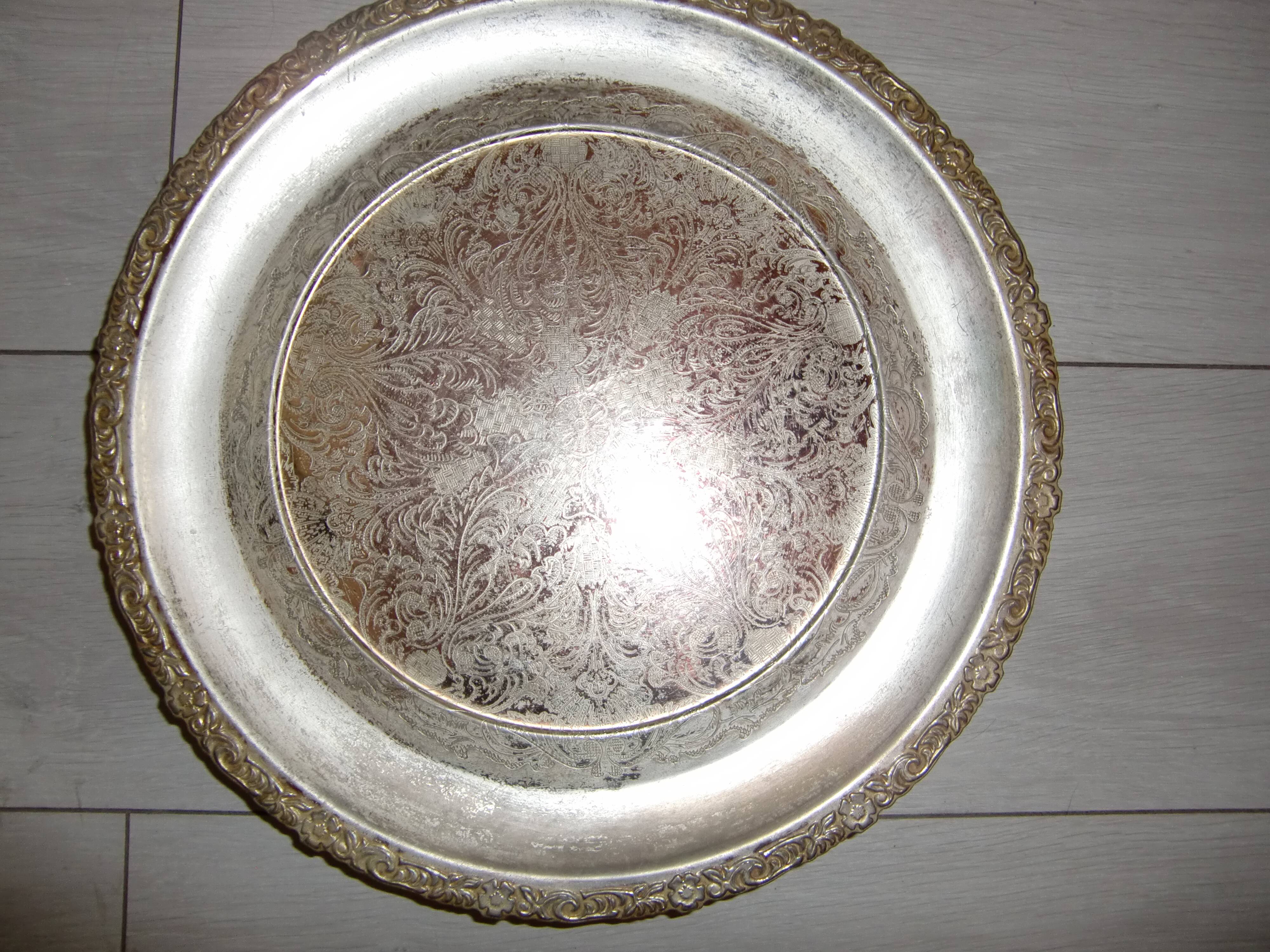 Large silver metal tray raised by a central foot