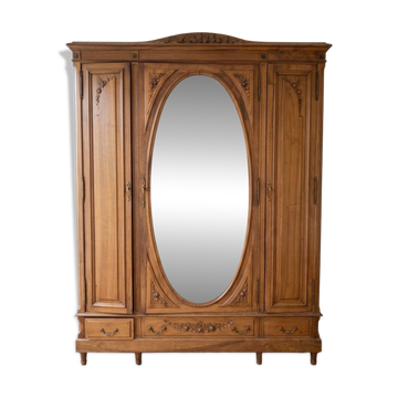 Antique solid wood wardrobe with an oval mirror.