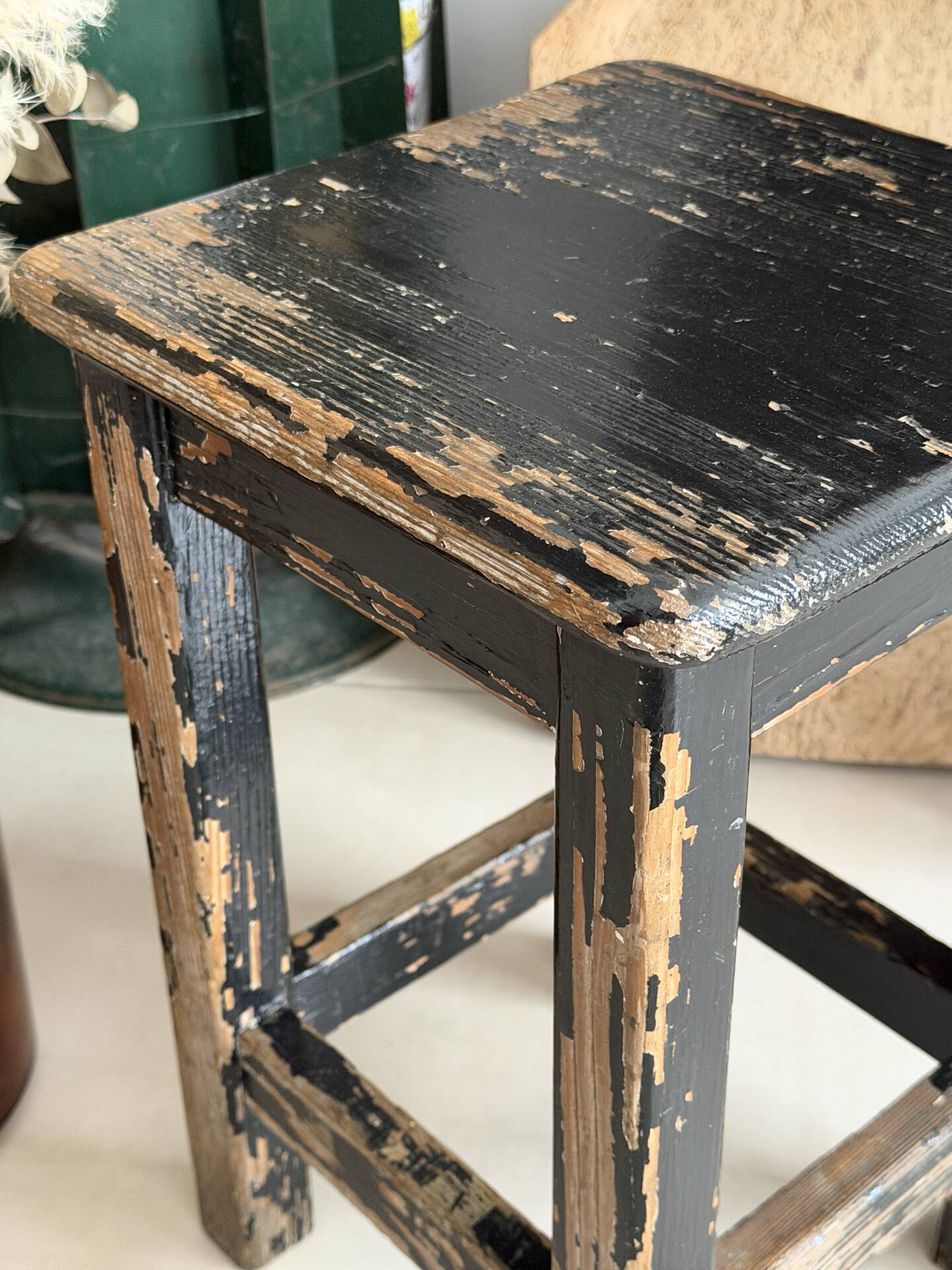 Solid wood stool with a worn black patina.
