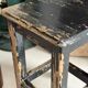 Solid wood stool with a worn black patina.