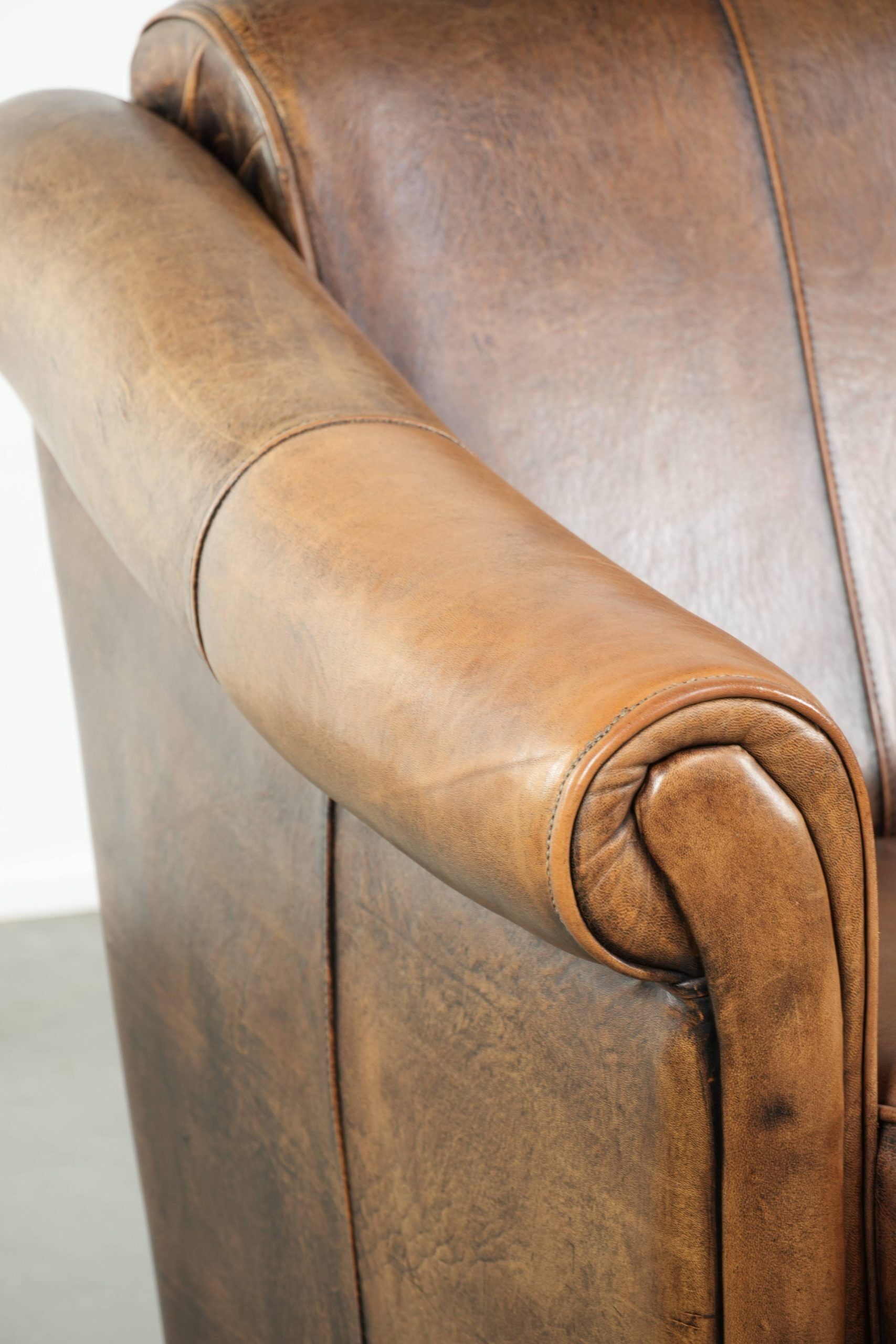 Fauteuil en peau de mouton magnifiquement conçu et confortable, avec un look intemporel et une finition de passepoil assortie.