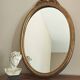 Vintage oval mirror with a carved wooden frame in gold, decorated with a bow.