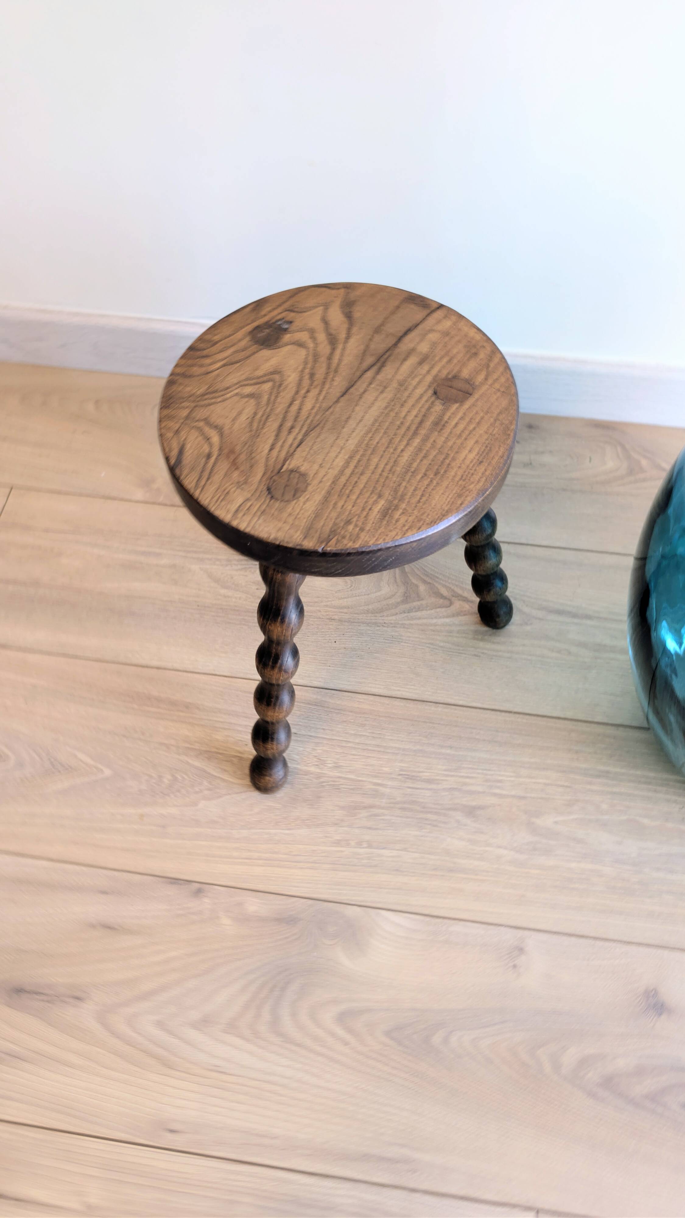 Small wooden tripod stool with turned legs, country style.