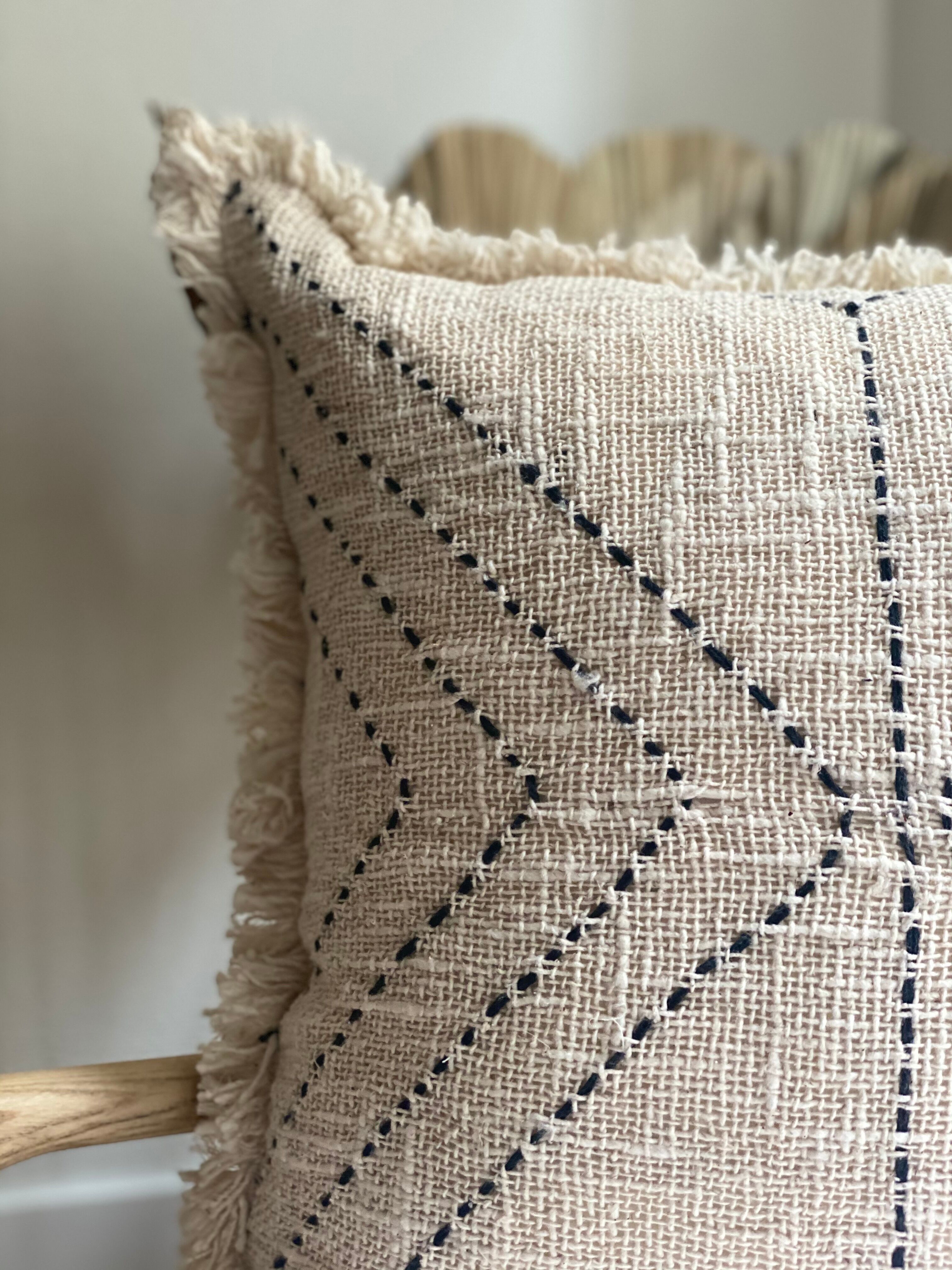 Embroidered and fringed linen cushion with an ethnic motif