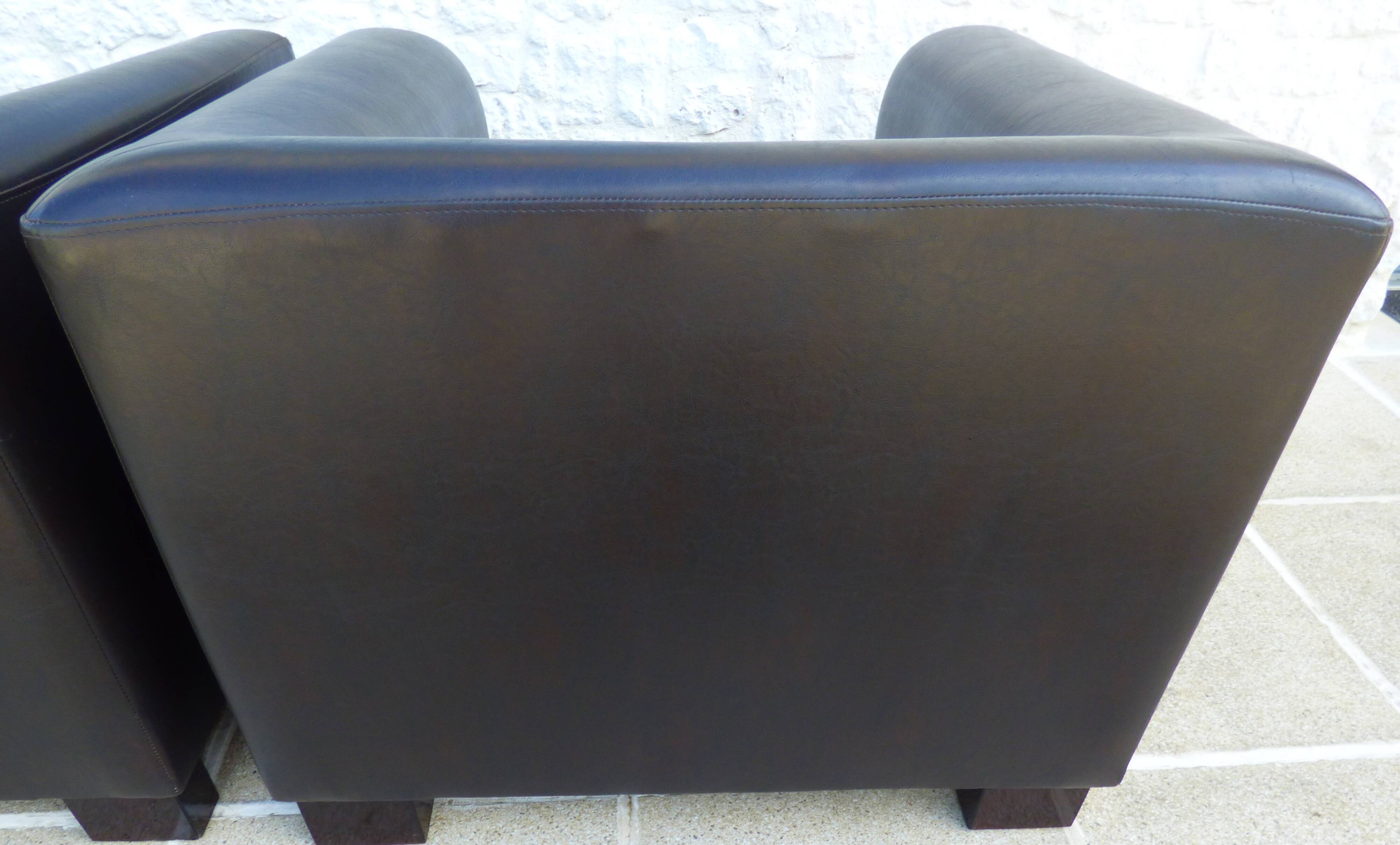 2 club armchairs with a chocolate faux leather seat and backrest and wooden legs.