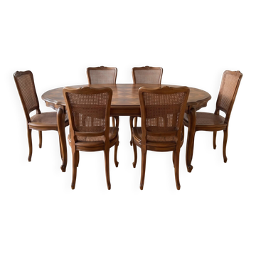 Oval dining table and 6 caned chairs in Louis XVI style made of wood.