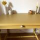 Desk table from the late 19th century, painted mustard, with turned stretcher.
