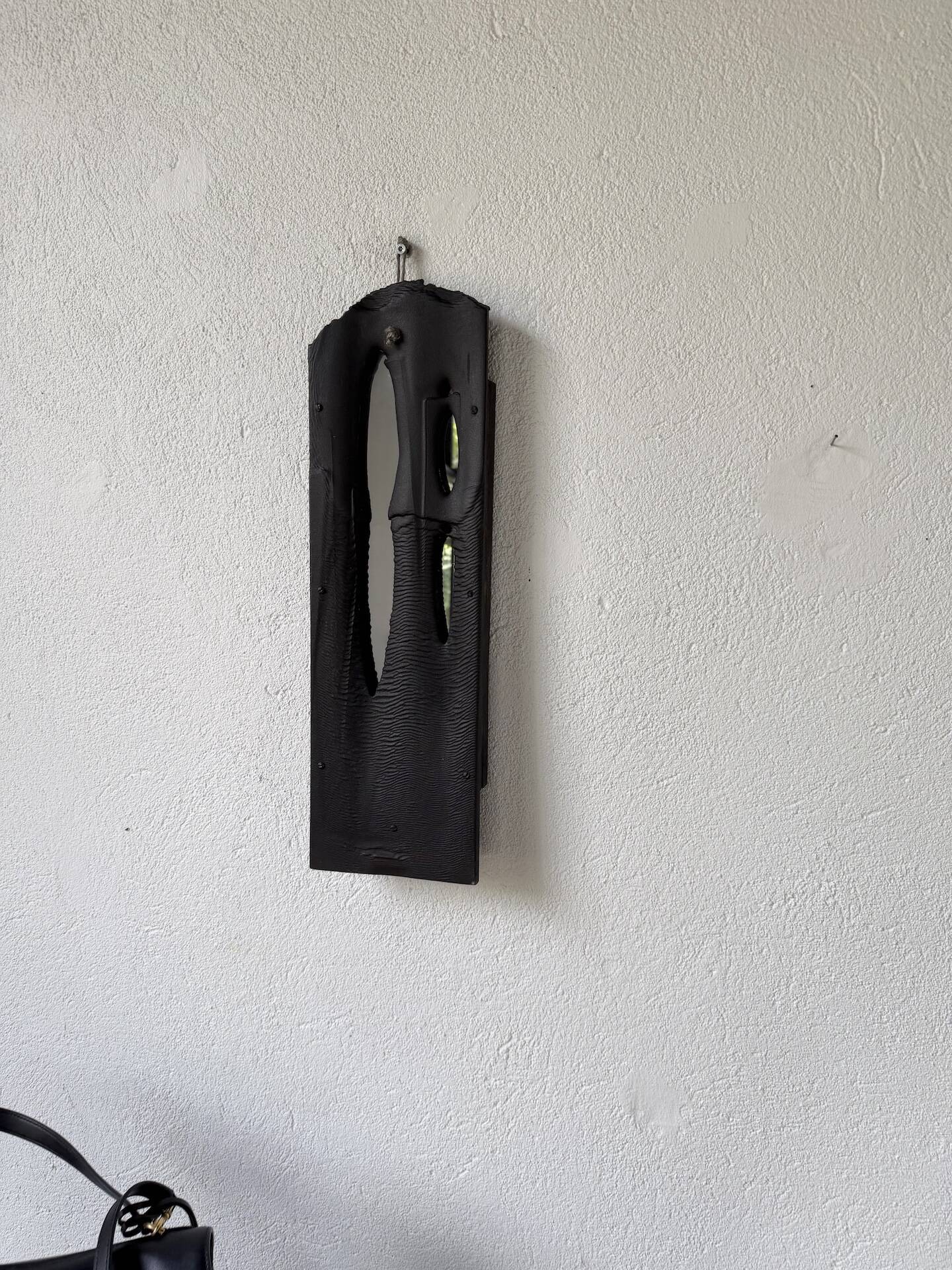 Brutalist hammered mirror, free-form, patinated metal.