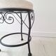 Black iron stool/pouf with its boucle fabric cushion.