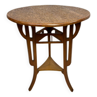 Round Art Nouveau coffee table with a sculpted top.