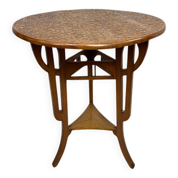 Round Art Nouveau coffee table with a sculpted top.